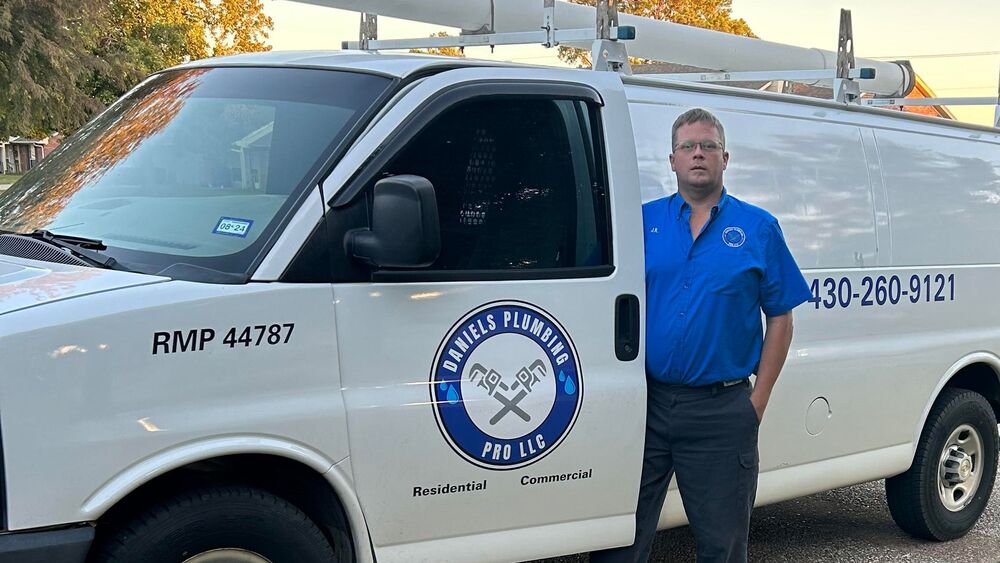 A plumber stands in front of a white van. The van displays the logo and contact information for a water line repair service. The plumber looks confident and ready to tackle any water line issue.